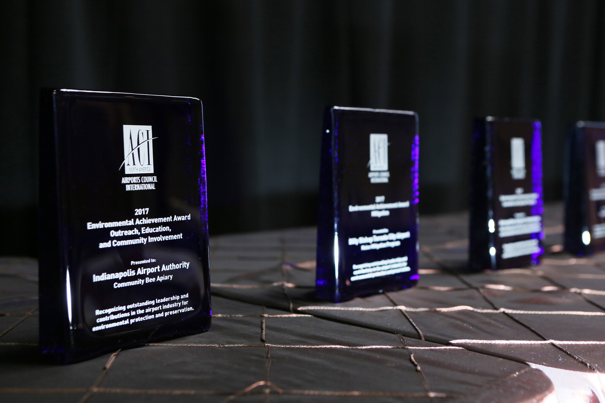 ACI-NA's Environmental Achievement Awards glass awards in a row on a table